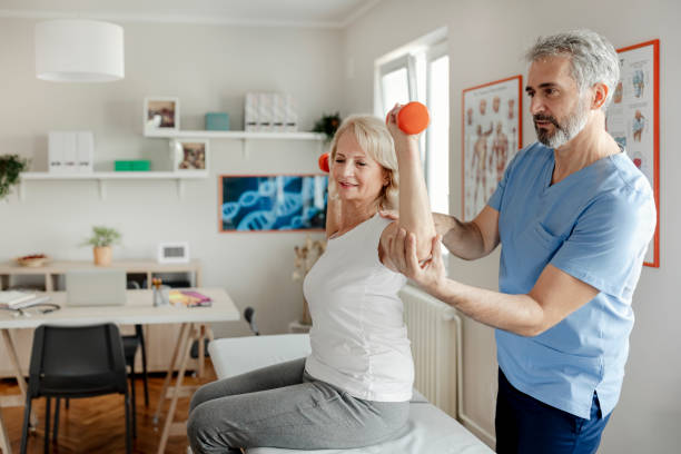 femme âgée utilisant des haltères avec l’aide d’un physiothérapeute - scrubs professional sport indoors healthcare and medicine photos et images de collection