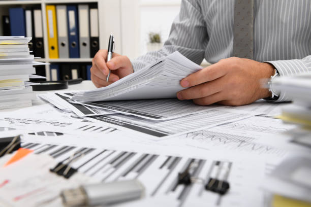 istock business concept - businessman working with reports in office, table and workspace close view, analyzing financial data, writes and counts 1289867058