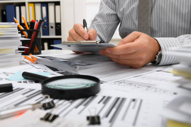 istock business concept - businessman working with reports in office, table and workspace close view, analyzing financial data, writes and counts 1289867116