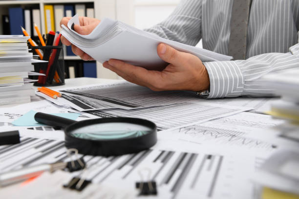 istock business concept - businessman working with reports in office, table and workspace close view, analyzing financial data, writes and counts 1289867224