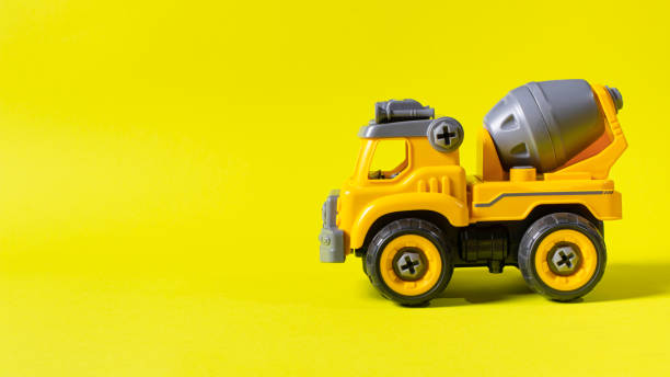 istock Construction machine concrete mixer made of plastic on a yellow background with a place for text copy space. Toy with cogs and screwdriver, which can be disassembled into details. Toy-designer. Banner for toy store 1289868740