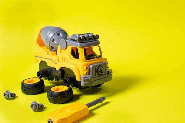 istock Construction machine concrete mixer made of plastic on a yellow background with a place for text copy space. Toy with cogs and screwdriver, which can be disassembled into details. Toy-designer. Banner for toy store 1289868764