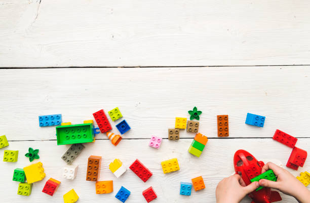 istock Top view on child's hand playing with multi-color plastic bricks at the table. 1289868974