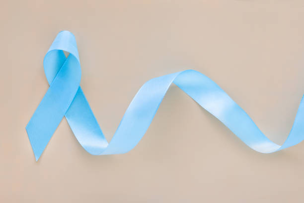 istock Light blue color ribbon bow curl on pastel orange isolated background with copy space. Lymphedema and Prostate Cancer Awareness month symbol. Healthcare medical and insurance concept. Male cancer. 1289869547