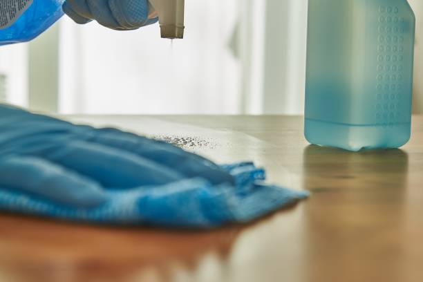 istock Person disinfecting a table with disinfectant. Cleaning a surface with disinfectant. Coronavirus precaution. 1289869580