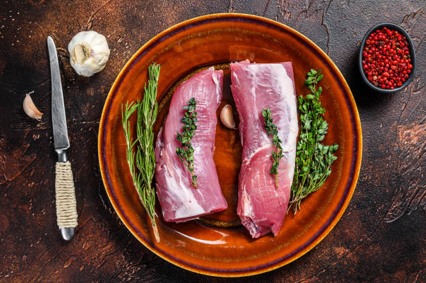свежее свиное мясо вырезки с розмарином и тимьяном. темный фон. вид сверху - veal raw meat pink стоковые фото и изображения