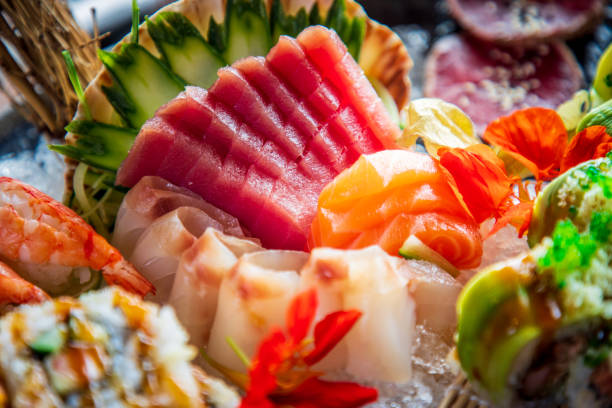rohe thunfischscheiben neben sashimi und nigiri auf eis - tuna raw portion prepared fish stock-fotos und bilder
