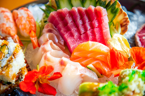Raw tuna slices served alongside nigiri, sashimi and sushi rolls on ice