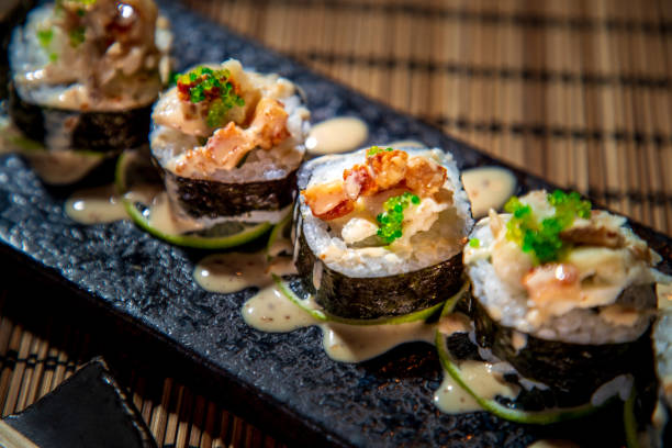 close-up of sushi rolls in nori lined up on rectangle sushi plate - sushi imagens e fotografias de stock