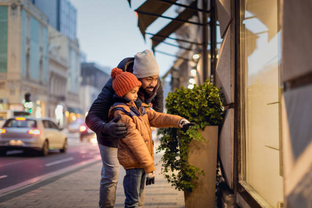 Young man with his son in Christmas shopping Christmas time. Father and son spending time together, walking on the street, shopping for Christmas present holiday shopping stock pictures, royalty-free photos & images