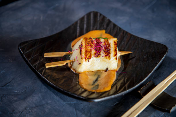 Sea bass fillet on miso barbeque sauce in plate Sea bass fillet pierced with wooden toothpicks on miso barbeque sauce in rectangle plate, chopsticks on the rest miso sauce stock pictures, royalty-free photos & images