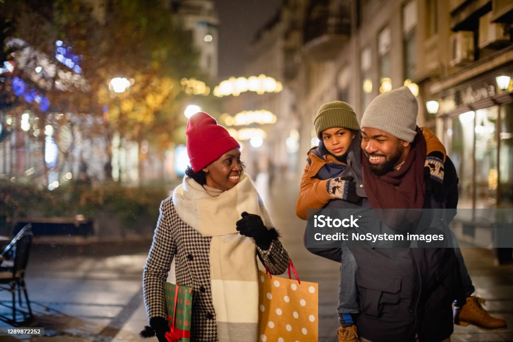 Family Christmas Shopping Christmas time. Mother, father and their son spending time together, walking on the street, shopping for Christmas present. Retail Stock Photo