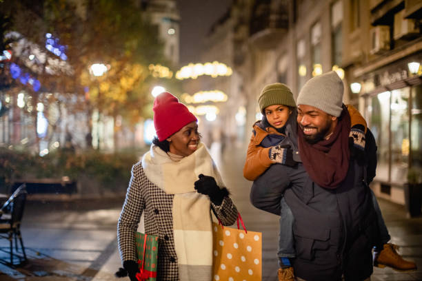 Family Christmas Shopping Christmas time. Mother, father and their son spending time together, walking on the street, shopping for Christmas present. holiday shopping stock pictures, royalty-free photos & images
