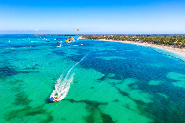 Tourists parasailing near Bavaro Beach, Punta Cana in Dominican Republic. Aerial view of tropical resort Tourists parasailing near Bavaro Beach, Punta Cana in Dominican Republic. Aerial view of tropical resort. punta cana stock pictures, royalty-free photos & images