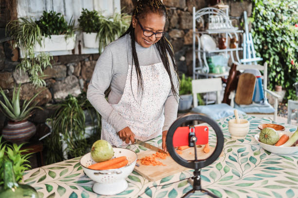 istock African senior woman cooking outdoor while streaming online for webinar masterclass lesson at home - Food and influencer concept - Focus on face 1289873589