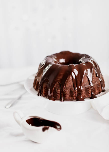 istock Dark chocolate cake covered with icing on a white stand. Selective focus. 1289874778