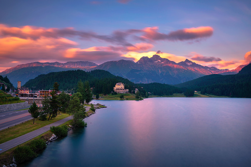 Colorful sunset above lake St. Moritzersee with Swiss Alps and a mountain hotel and restaurant. Long exposure.