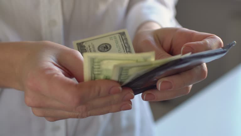 Woman counting dollar banknotes from black leather wallet