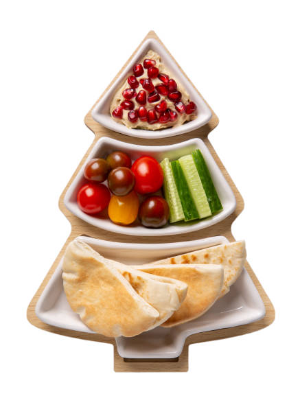 istock Hummus with vegetables and pita served on Christmas tree plate isolated on white background. Festive holiday snack. Top view. 1289878639