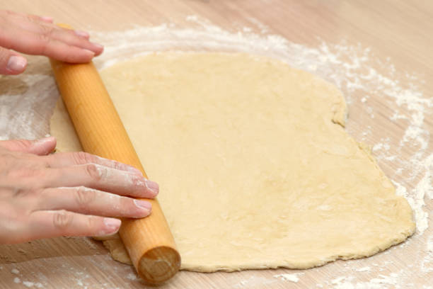 istock Women's hands roll out the dough with a rolling pin 1289880658
