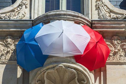 French tricolor formed by three umbrellas against the wall of a house: Jonzac, France