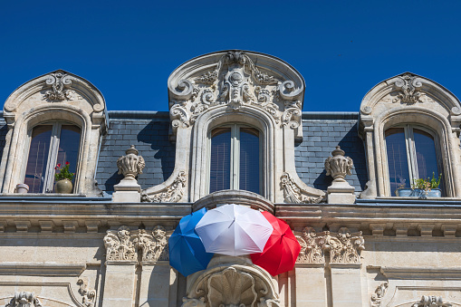 French tricolor formed by three umbrellas against the wall of a house: Jonzac, France