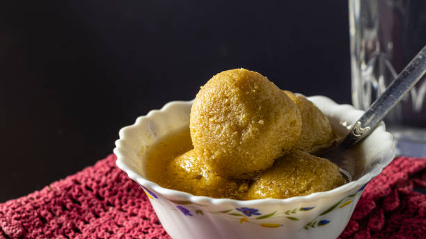 rosogolla - the most famous Indian or Bengali sweets the most famous Bengali or Indian sweets - Rasgulla made with date palm jaggery or nolen gur in a bowl on dark background rosogolla stock pictures, royalty-free photos & images