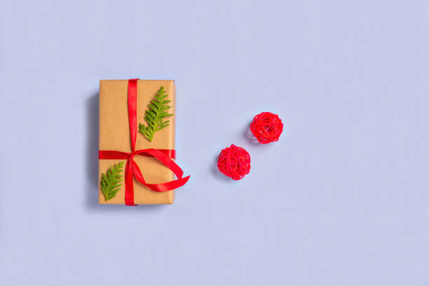 istock Gift boxes wrapped with paper kraft, red ribbon, thuja twigs, balls on a light background. Top view. Presents for the holiday, Christmas. 1289885000