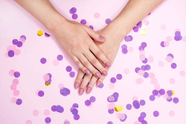 istock Stylish women's manicure in pink tones on a background with multicolored confetti 1289886098