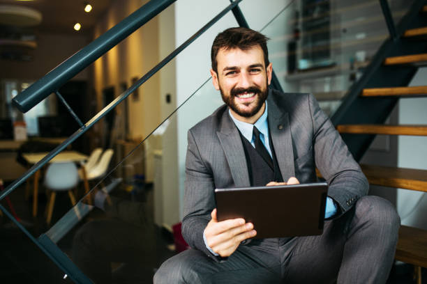 istock Smiling young businessman looking at tablet inside modern office 1289886250