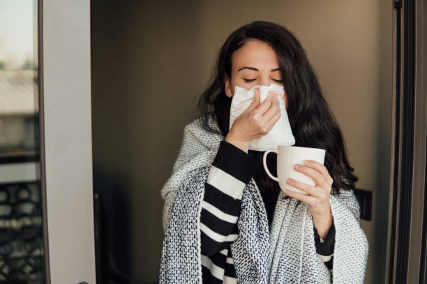 istock Sick woman covered with blanket blowing her nose 1289886539