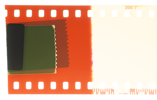 A sticker at the end of a roll of photographic negative film: close-up showing light leak and sproket holes.
