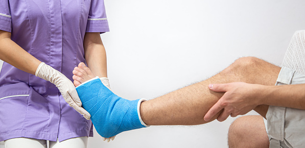 Close up of a man's leg in a cast and a blue splint after bandaging in a hospital.