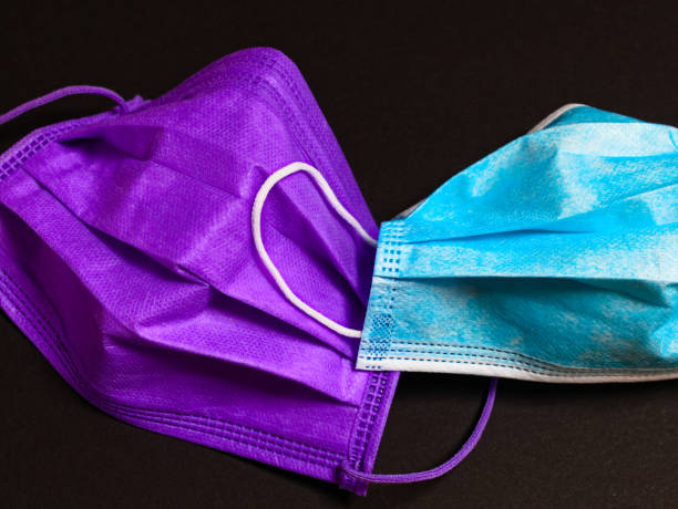 istock a violet and a blue-white surgical mask against a black background 1289891950
