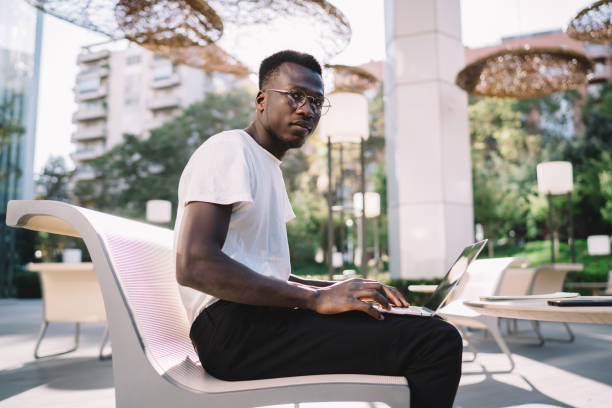 istock Serious pensive dark skinned student concentrated on doing homework task online on cafe terrace using technology, pensive african american hipster guy using laptop computer for browsing outdoors 1289894282