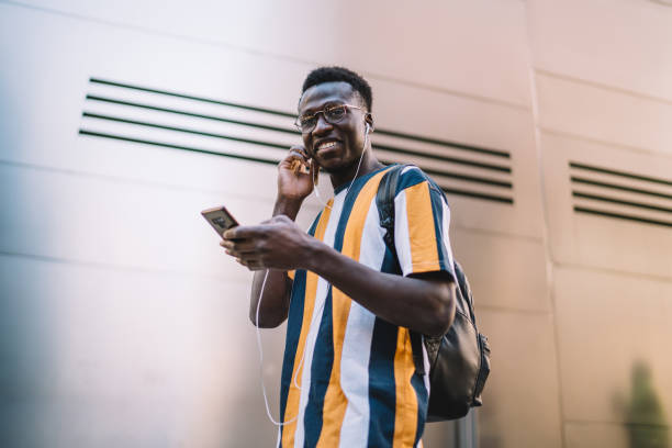 istock Joyful black man using cellphone and listening to music next to wall 1289894376