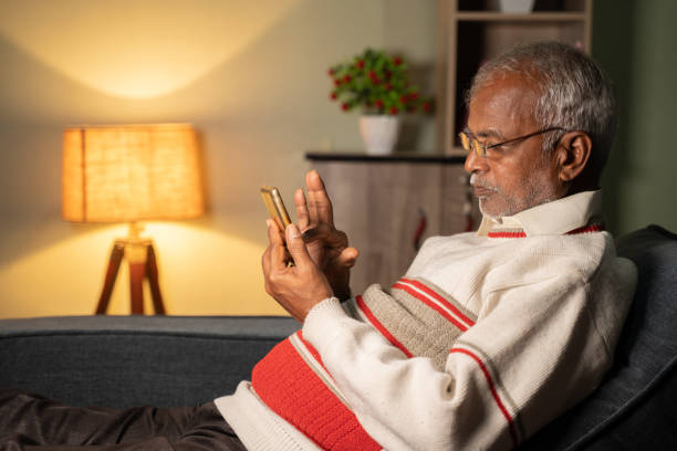 old man busy using mobile phone at home while sleeping on sofa - concept of senior people using technology, internet and social media. - mobile phone text messaging people asian ethnicity imagens e fotografias de stock