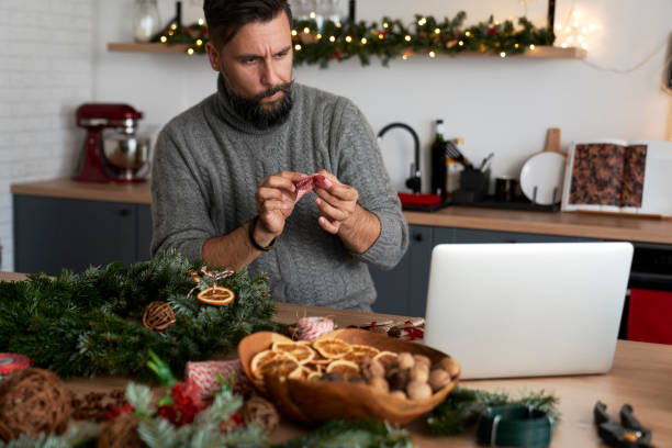 istock Man learning to decorate a Christmas wreath using decorative ribbon 1289900713