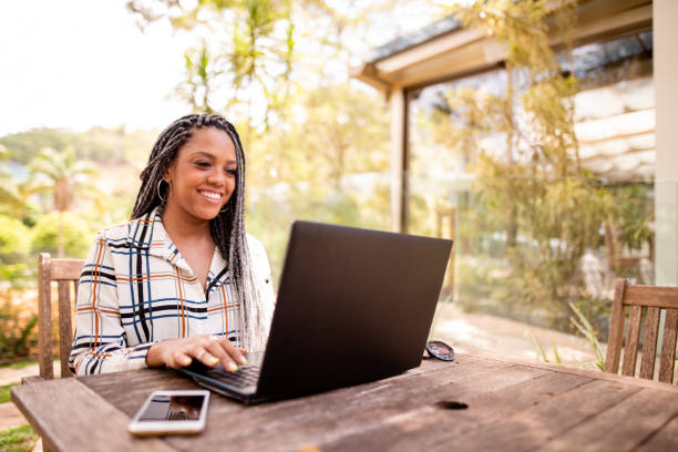 Black woman using laptop and cell phone outdoors