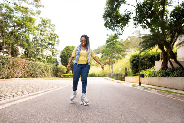 donna nera rollerblading all'aperto in una strada - pattinaggio in linea foto e immagini stock