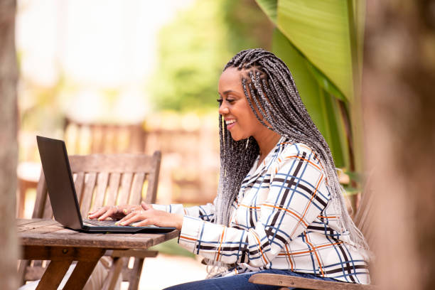 istock Black woman using laptop and cell phone outdoors 1289903076
