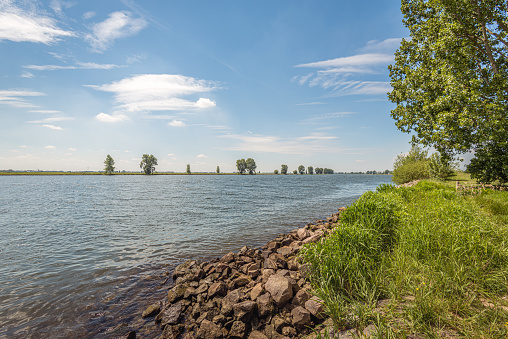 Stones on the banks of a Dutch river provide protection against erosion. The photo was taken in the spring season at the Bergsche Maas river in the province of Noord-Brabant.