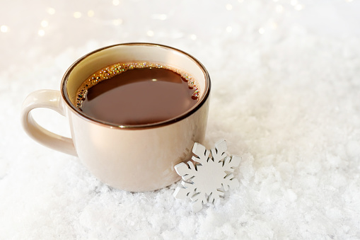 Holiday christmas cup of coffe with wooden snowflake on snow background. concept of winter morning
