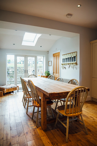 A wide angle view of a country style kitchen in a family home in Northumberland in the North East of England with a long dining table for a large family.