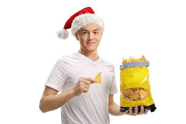istock Guy with a santa claus hat holding a bag of chips and pointing 1289908725