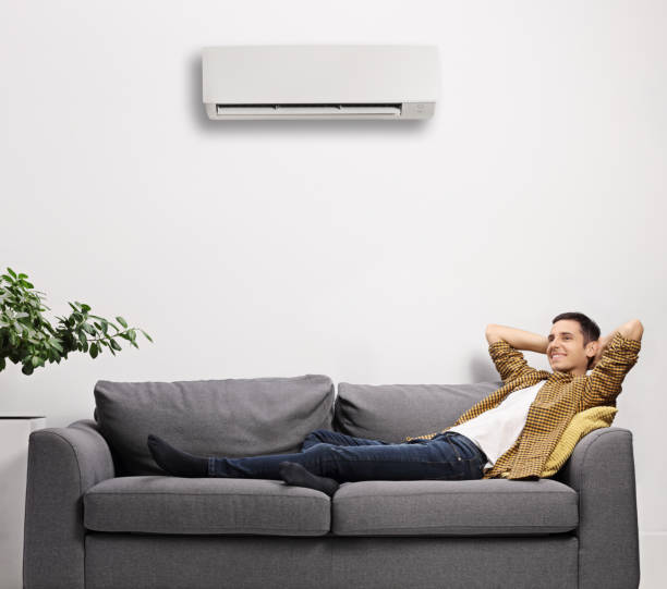istock Man enjoying on a sofa with air conditioning unit on the wall 1289908772