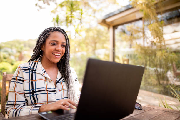 istock Black woman using laptop and cell phone outdoors 1289908932