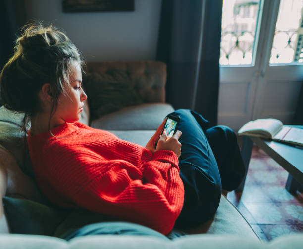 Woman staying home during COVID-19 pandemic Young woman at home photo editing selfie on mobile app photo editing screen stock pictures, royalty-free photos & images