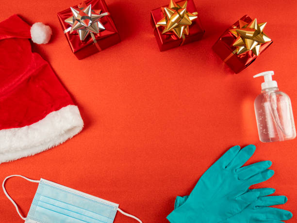 istock Flat lay and copy space on red background. Christmas coronavirus. Pandemic prevention with hand sanitizer, protective gloves and surgical mask. Christmas gifts from Santa Claus. Empty space for text. 1289910302