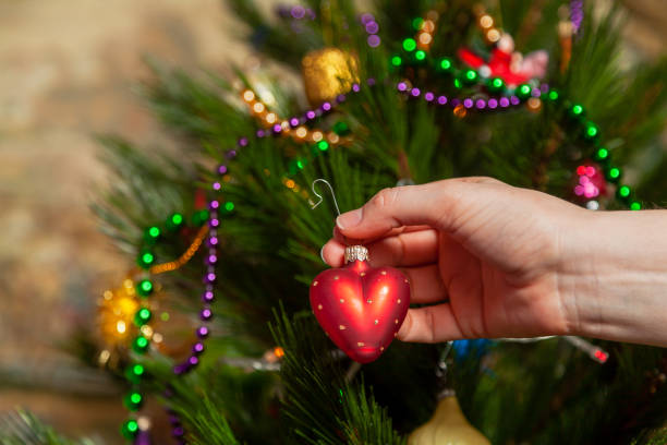 istock Hand hangs toy heart on Christmas tree 1289910377